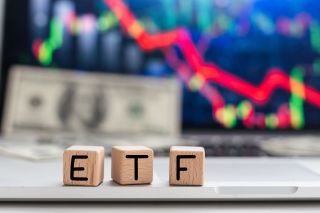 On a light background, graphs, charts and wooden cubes with the inscription ETF - Exchange Traded Fund.